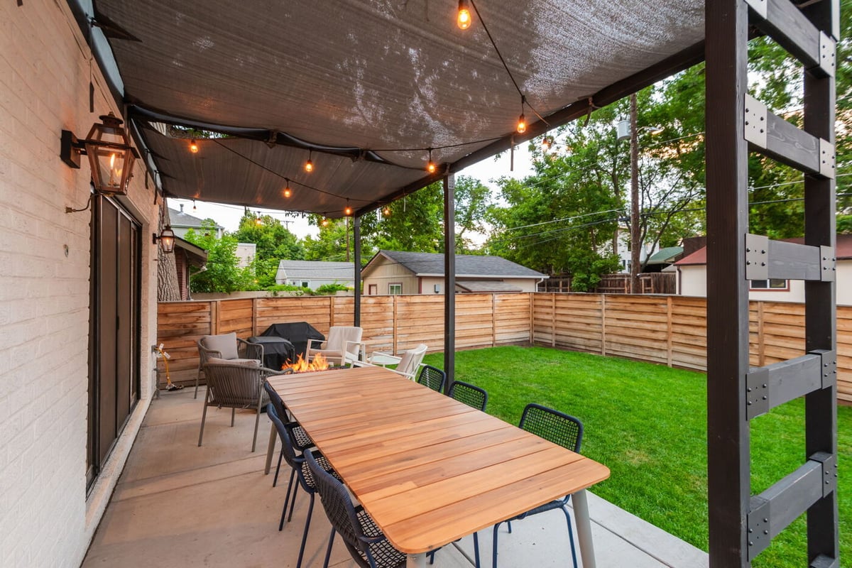 Denver pop top renovation covered patio with wood dining table, fire feature, and string lights by Cillessen Construction