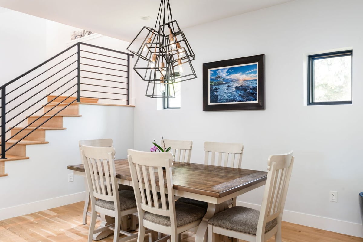 Denver pop top renovation dining area with wood table, modern chandelier, and staircase railing by Cillessen Construction