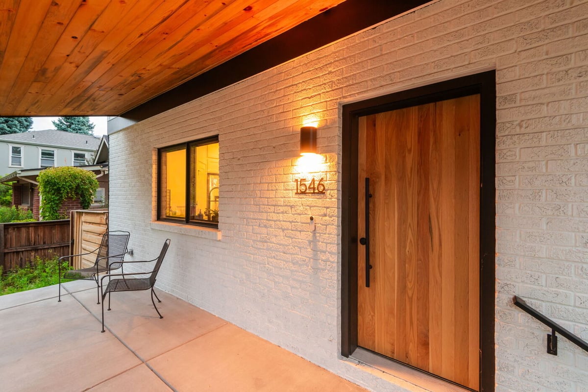 Denver pop top renovation front porch with wood entry door, brick exterior, and warm lighting by Cillessen Construction