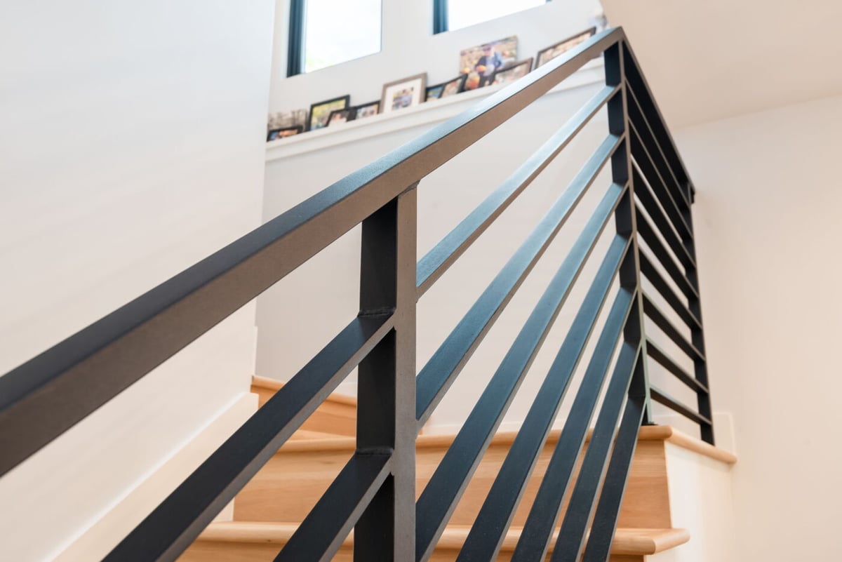 Denver pop top renovation interior staircase with black metal railing, wood steps, and bright open landing by Cillessen Construction