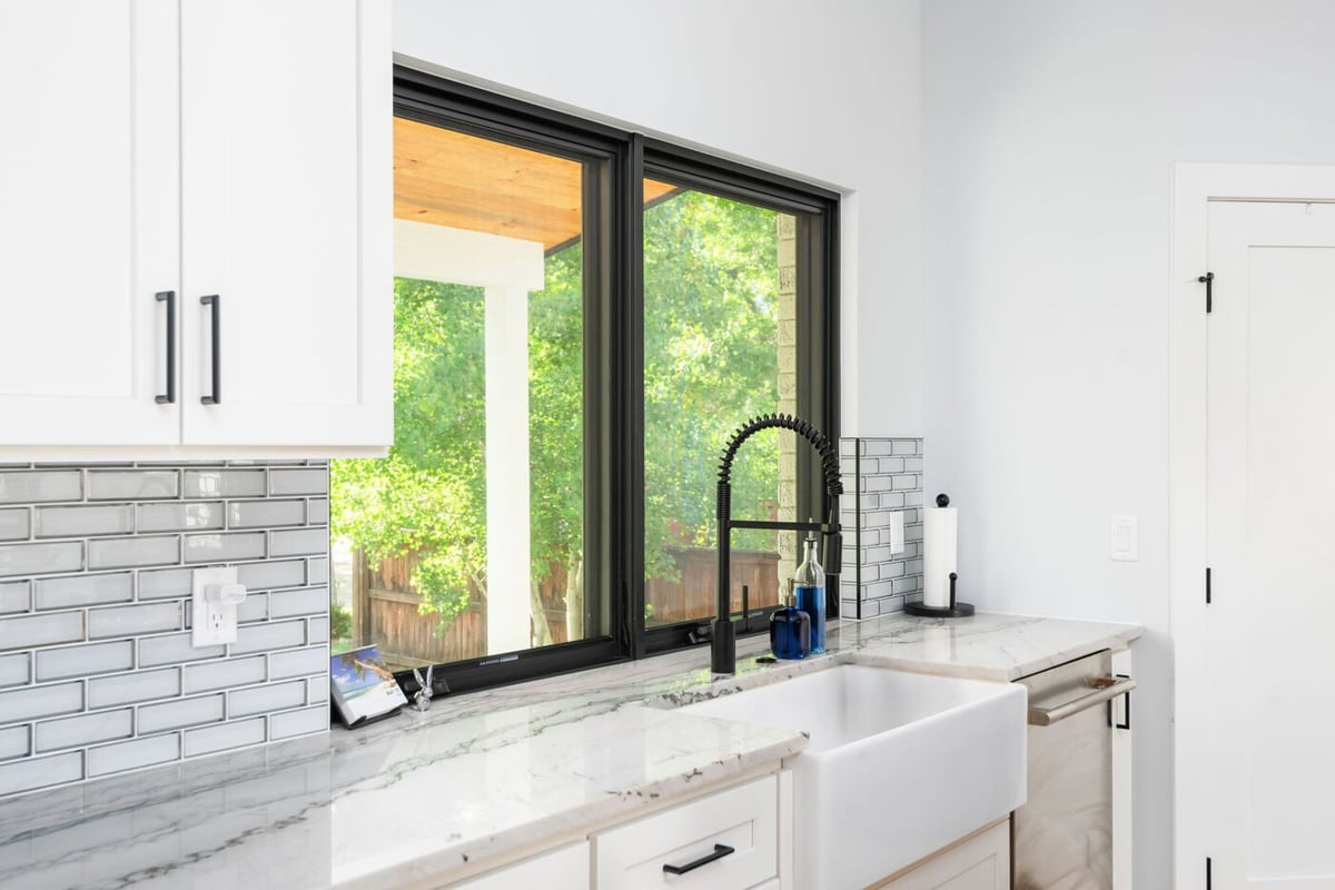 Denver pop top renovation kitchen sink with farmhouse sink, marble counters, and large window by Cillessen Construction