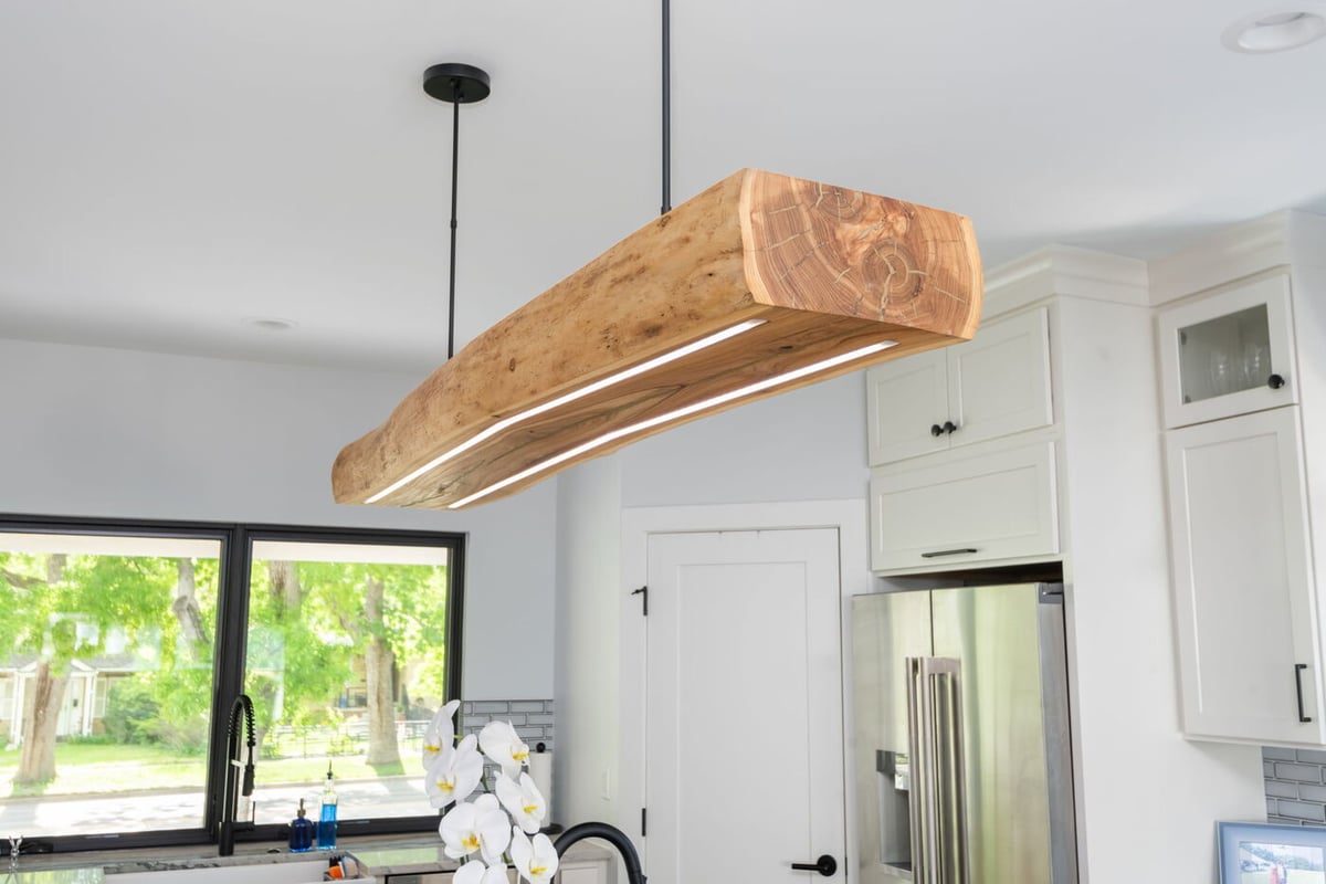 Denver pop top renovation kitchen with custom wood beam pendant light, white cabinets, and large window by Cillessen Construction