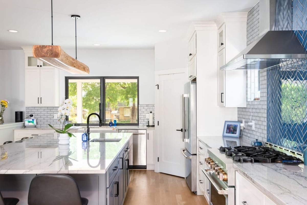 Denver pop top renovation kitchen with large island, white cabinetry, stainless appliances, and blue tile backsplash by Cillessen Construction