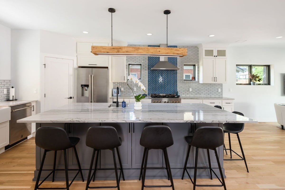 Denver pop top renovation kitchen with marble island, black stools, white cabinets, and blue tile by Cillessen Construction