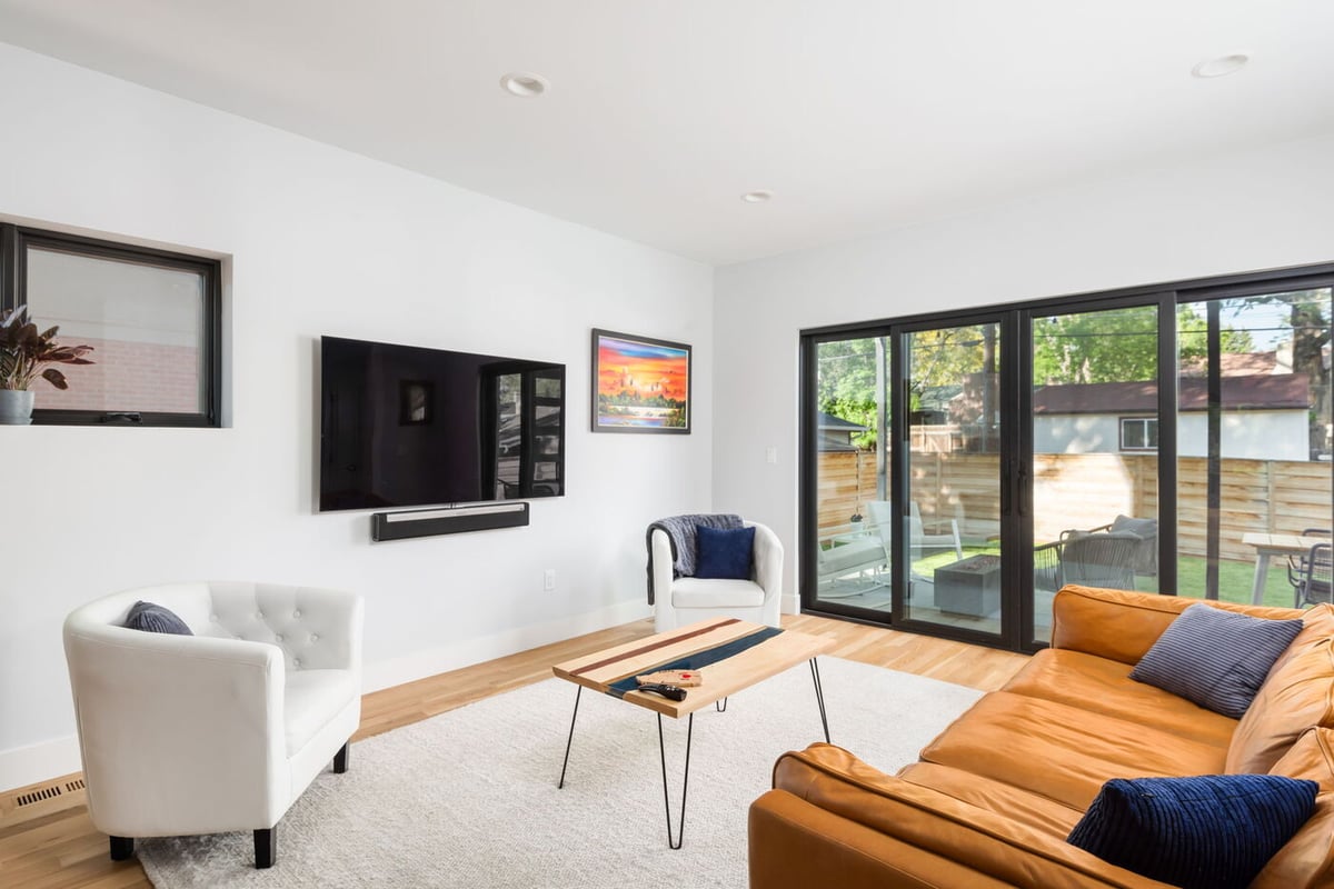 Denver pop top renovation living room with modern seating, wall-mounted TV, and patio access by Cillessen Construction