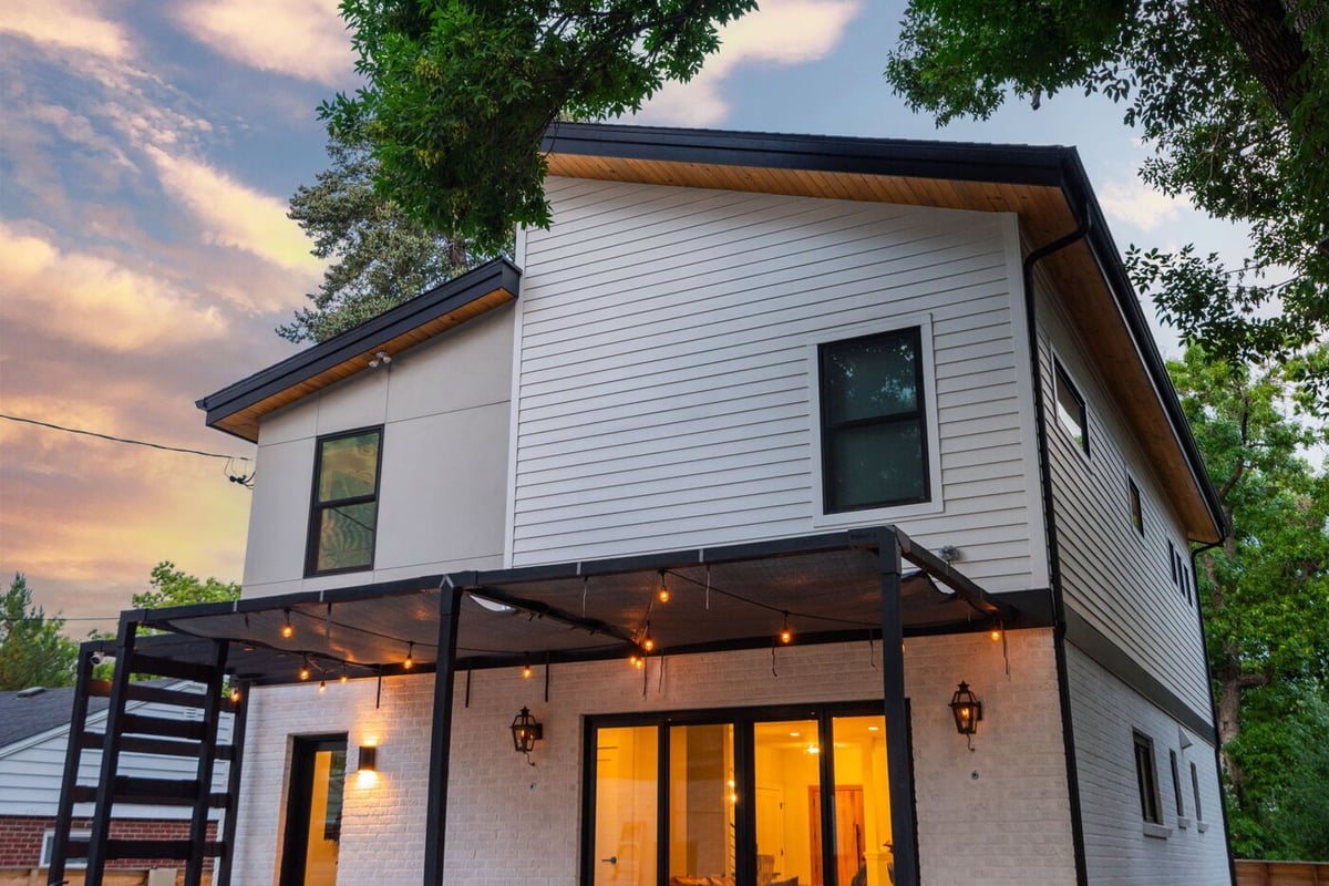 Modern Denver home exterior with covered patio and warm lighting at dusk by Cillessen Construction