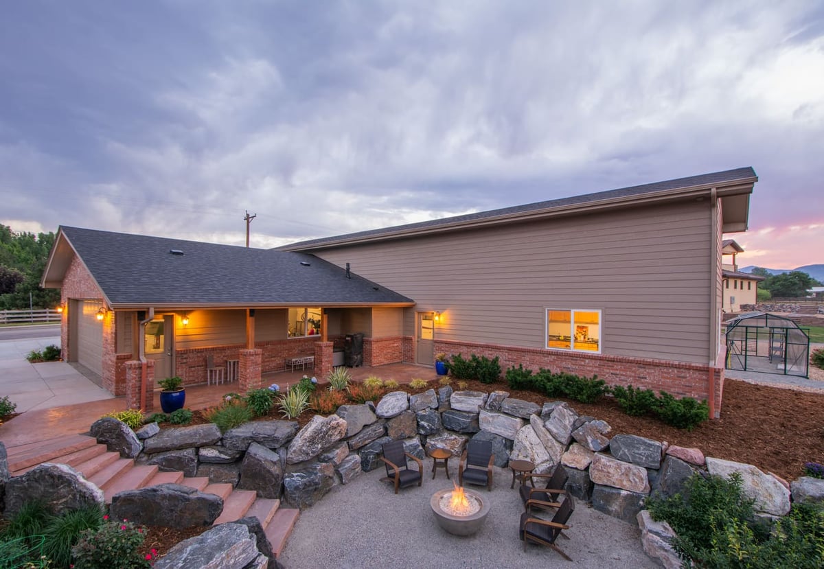 Backyard fire pit seating area with stone retaining walls next to garage build in Arvada, CO by Cillessen Construction