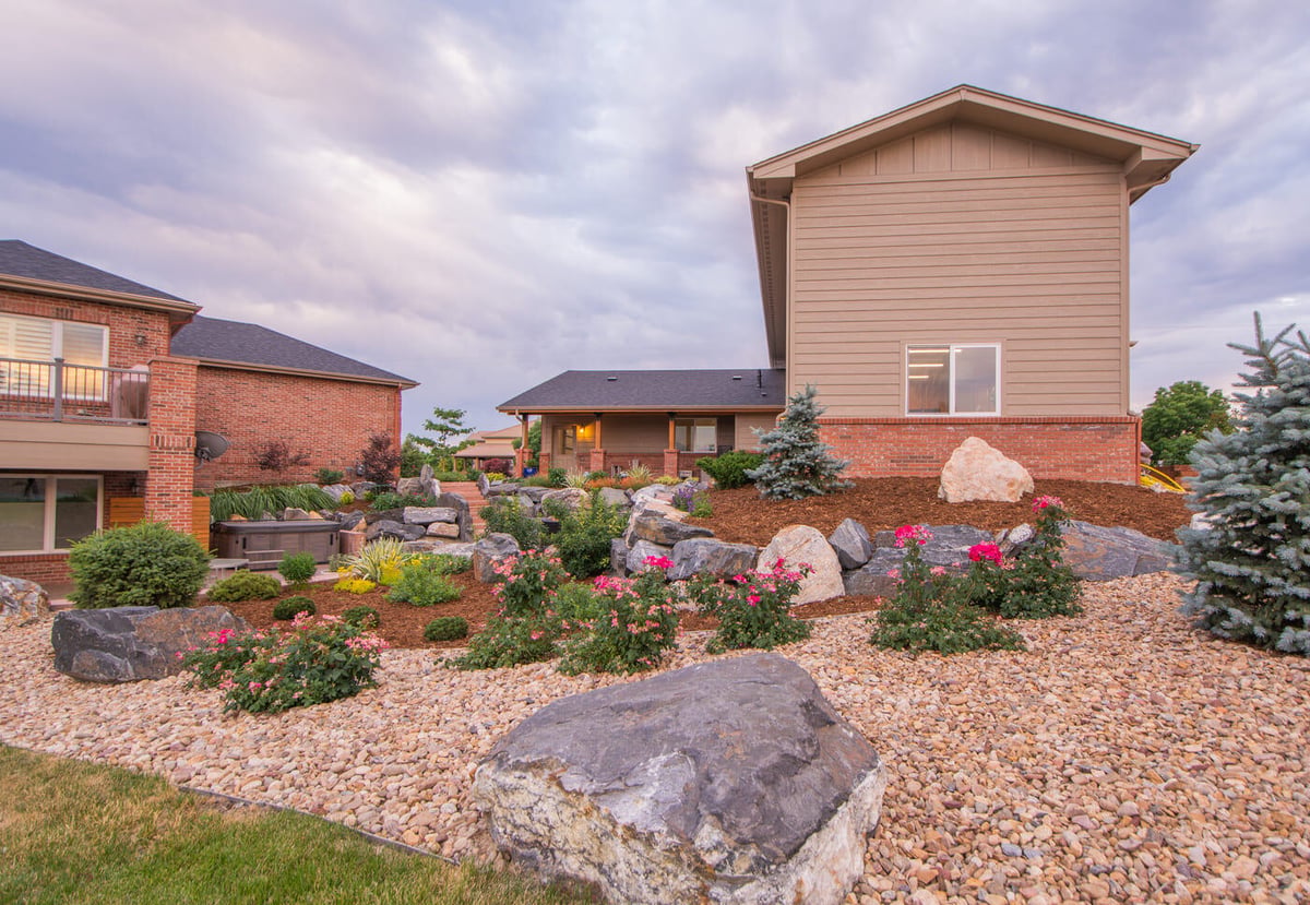 Backyard landscaping with rock features and plantings outside garage build in Arvada, CO by Cillessen Construction