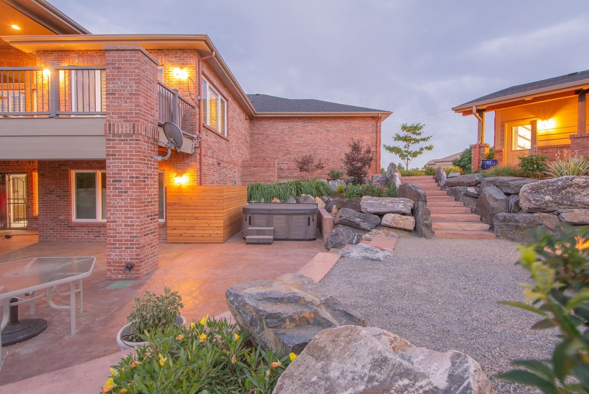 Backyard patio with hot tub and stone landscaping next to garage build in Arvada, CO by Cillessen Construction