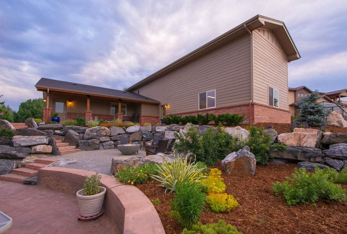 Landscaped backyard with stone retaining walls and patio next to garage build in Arvada, CO by Cillessen Construction