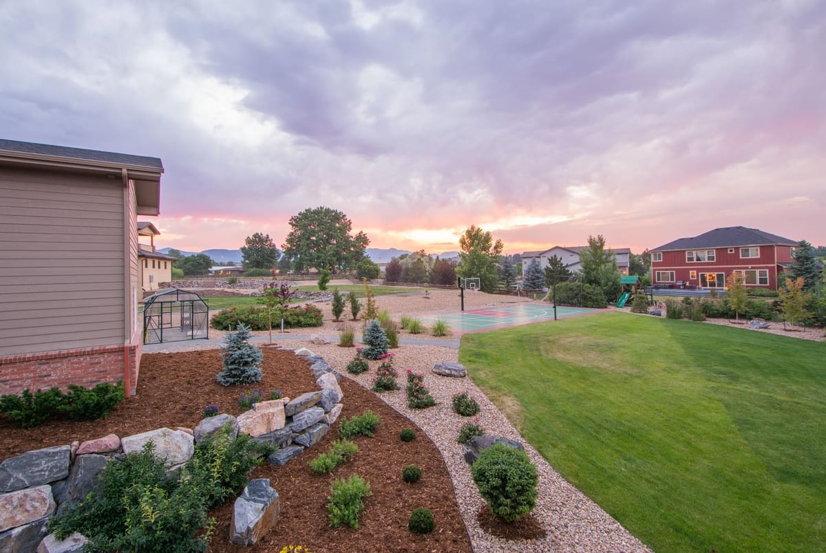 Landscaped yard with garden beds, greenhouse, and sport court outside garage build in Arvada, CO by Cillessen Construction