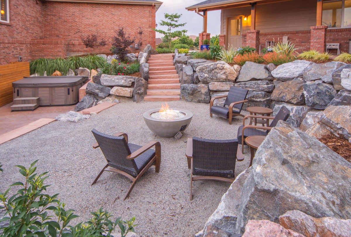 Outdoor seating area with fire pit and stone walls near garage build in Arvada, CO by Cillessen Construction