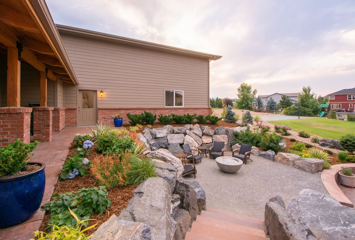 Sunken fire pit seating area with stone walls outside garage build in Arvada, CO by Cillessen Construction