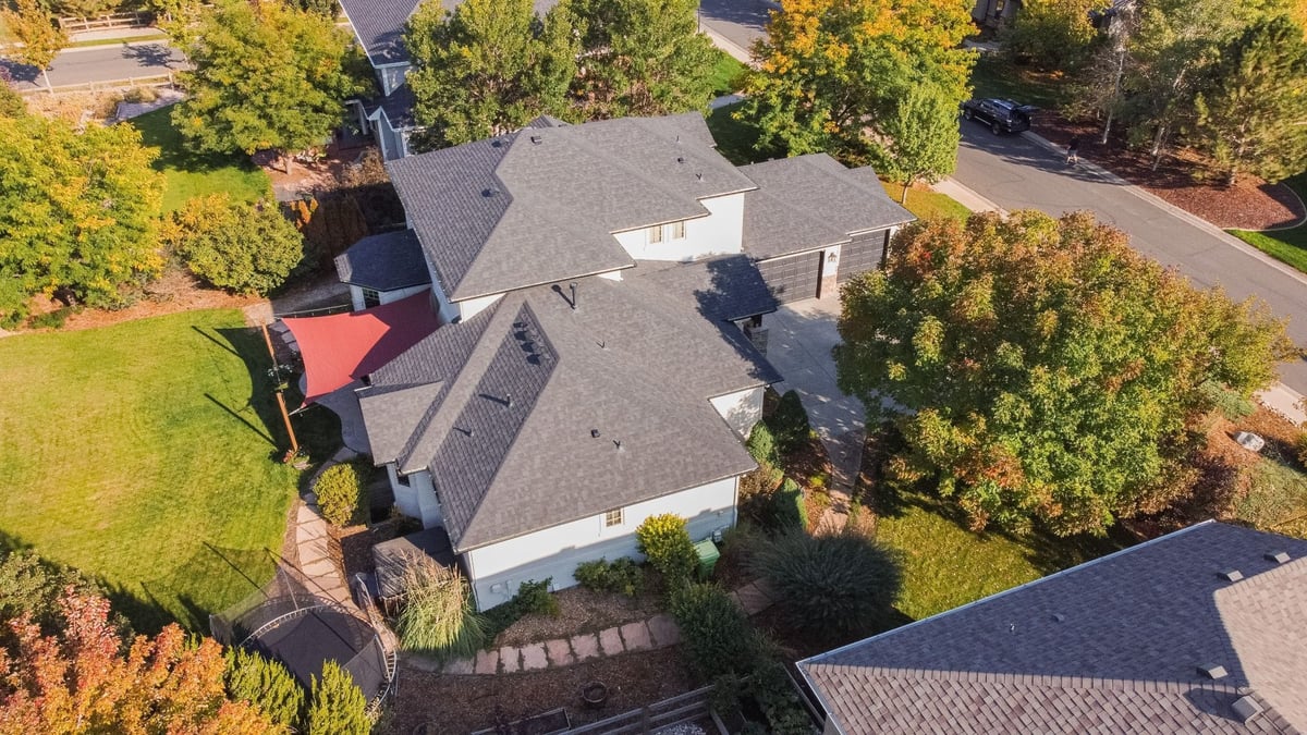 aerial perspective of home with exterior restoration roofing in denver colorado featuring red shade canopy and backyard landscaping