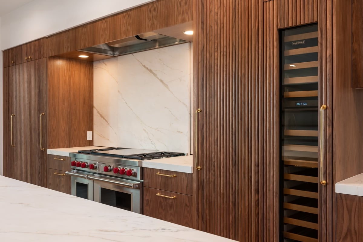 modern walnut kitchen cabinetry with marble backsplash in applewood village pop top renovation