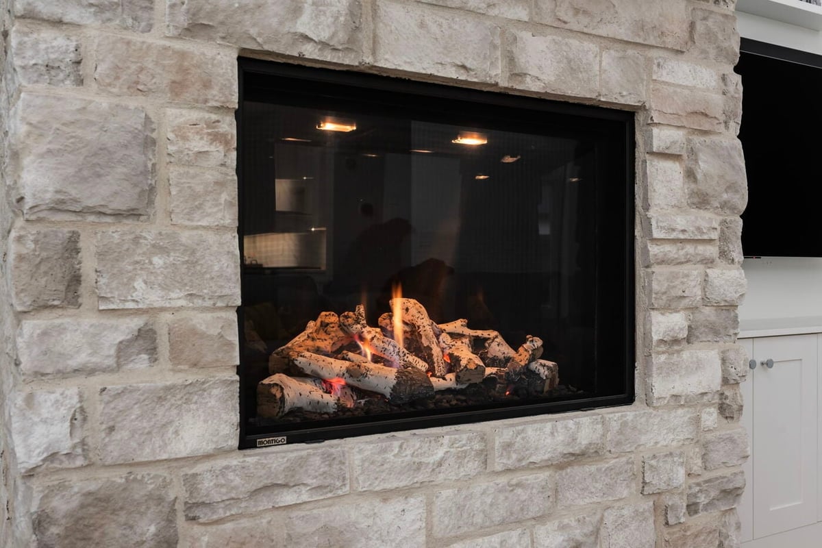Louisville, CO custom home close-up of modern stone fireplace with gas logs and built-in surround by Cillessen Construction
