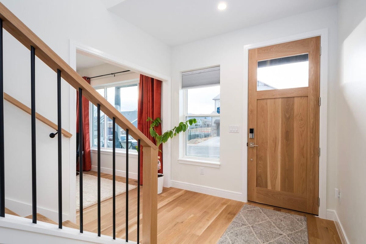 Louisville, CO custom home entryway with wood door, staircase, and natural light by Cillessen Construction