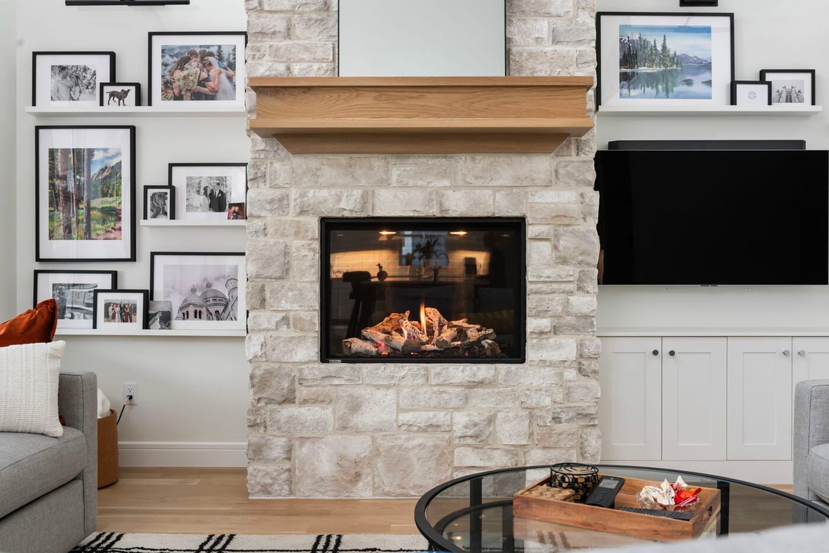 Louisville, CO custom home fireplace wall with wood mantel, gallery shelves, and contemporary finishes by Cillessen Construction