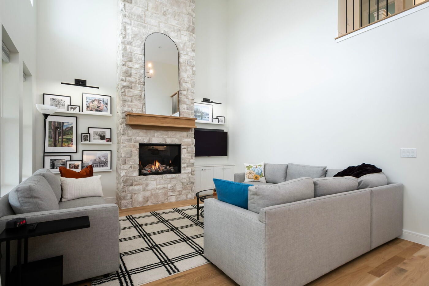 Louisville, CO custom home living room with stone fireplace, modern sofas, and gallery wall by Cillessen Construction