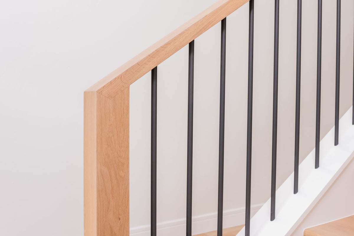 Louisville, CO custom home stair railing detail with wood cap and black balusters by Cillessen Construction