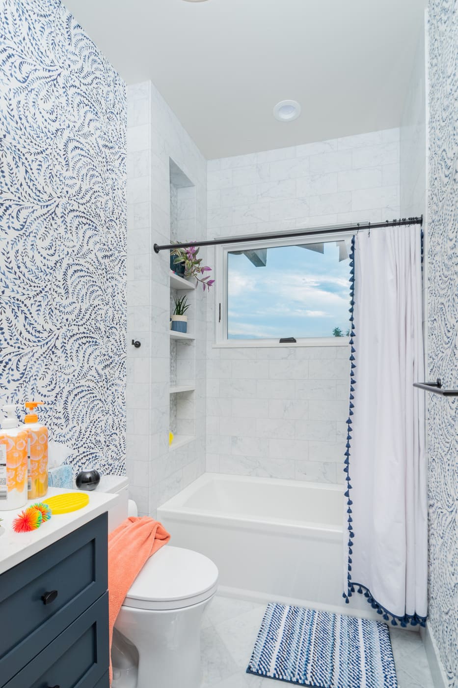 Genesee, CO renovation bathroom with patterned wallpaper, tub shower, and window by Cillessen Construction