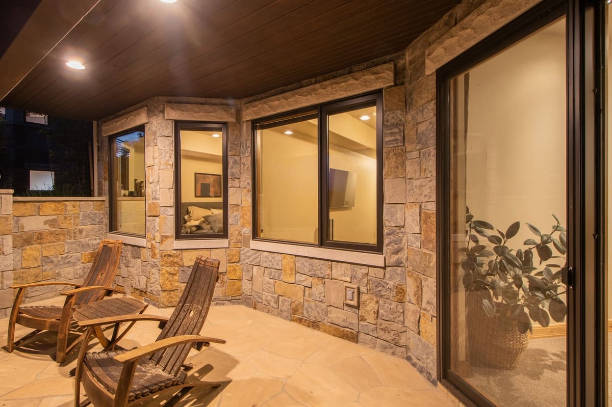 Genesee, CO renovation covered patio with stone walls, seating, and warm lighting by Cillessen Construction