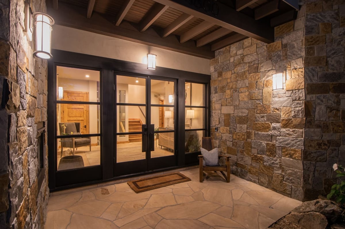 Genesee, CO renovation entry with stone walls, wood beams, and glass doors by Cillessen Construction