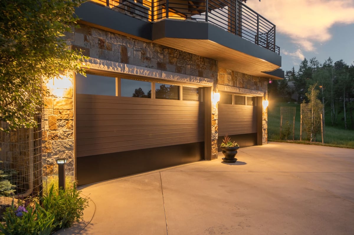 Genesee, CO renovation exterior with garage, stone facade, and evening lighting by Cillessen Construction