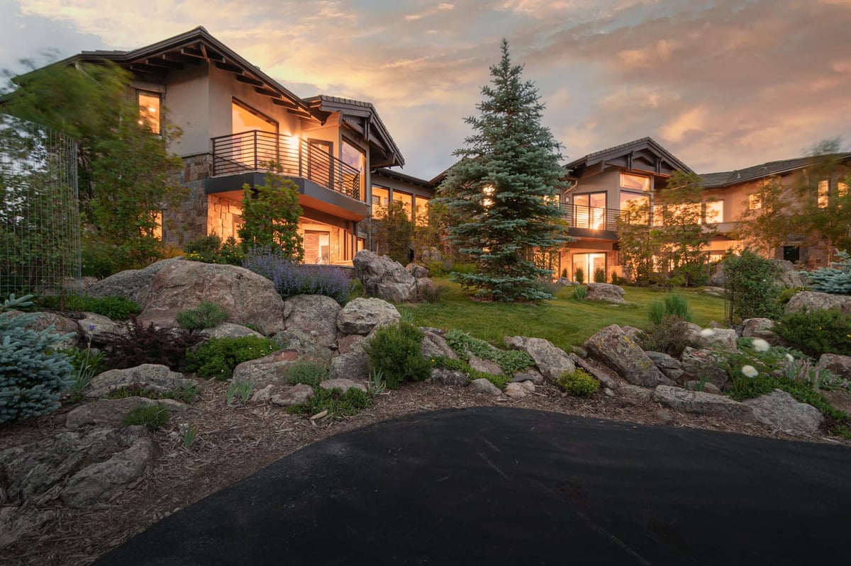 Genesee, CO renovation exterior with landscaped rocks and lit modern home at dusk by Cillessen Construction