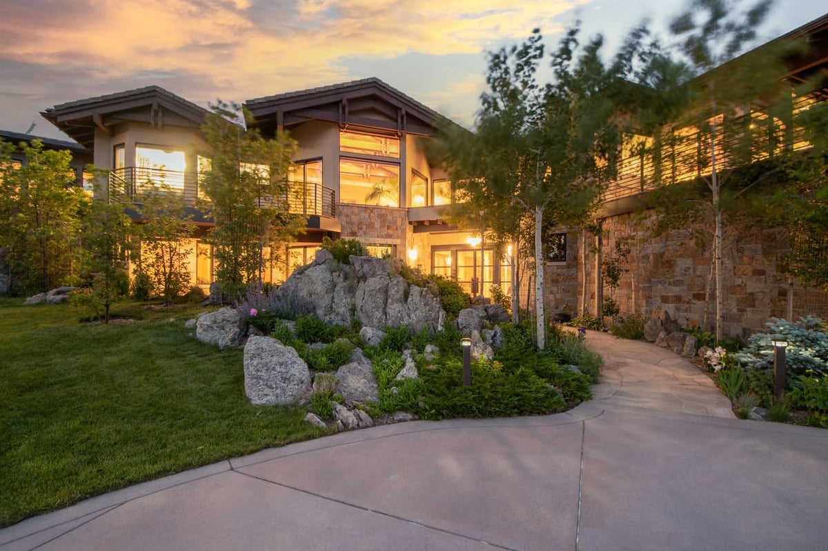 Genesee, CO renovation exterior with patio, landscaping, and glowing windows at sunset by Cillessen Construction