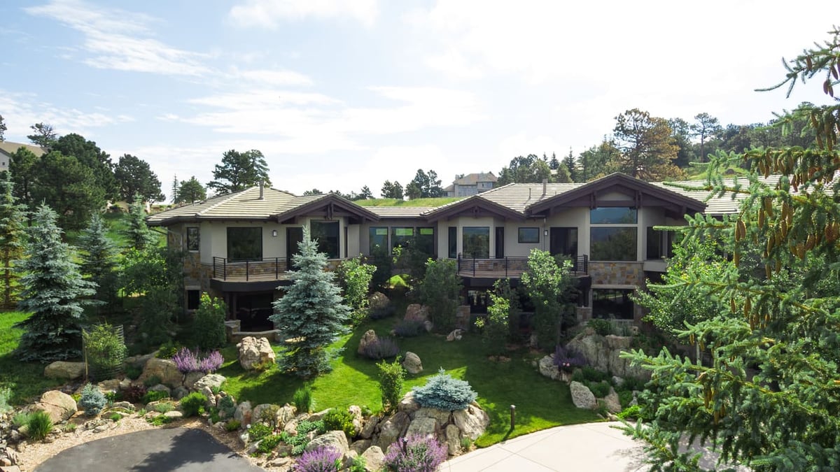 Genesee, CO renovation front exterior with stonework, decks, and lush landscaping by Cillessen Construction