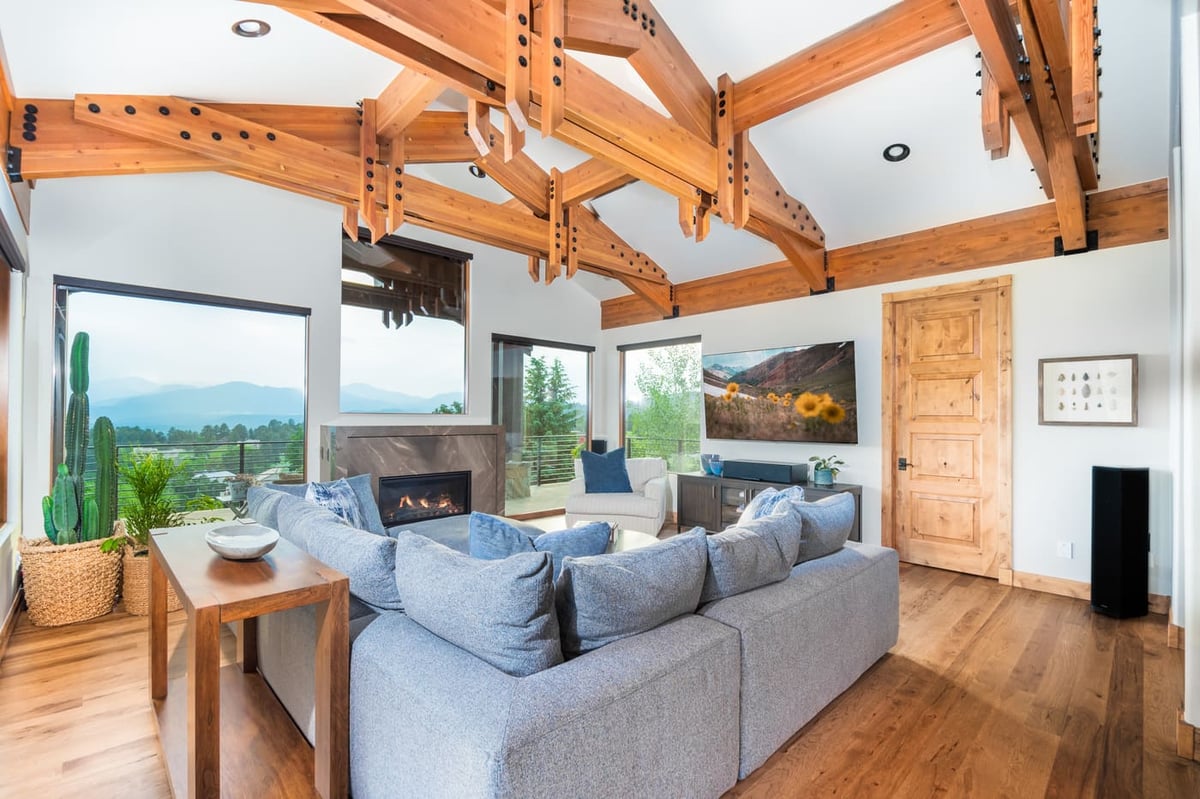 Genesee, CO renovation living room with exposed beams, fireplace, and open layout by Cillessen Construction