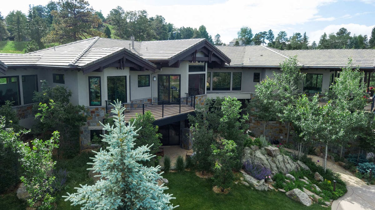 Genesee, CO renovation rear view with deck, stone exterior, and lush landscaping by Cillessen Construction