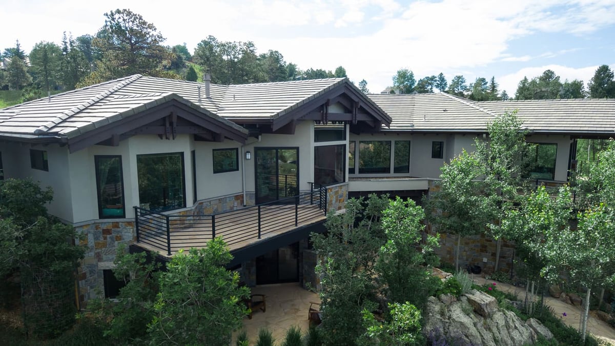 Genesee, CO renovation with elevated deck, stone exterior, and wooded setting by Cillessen Construction