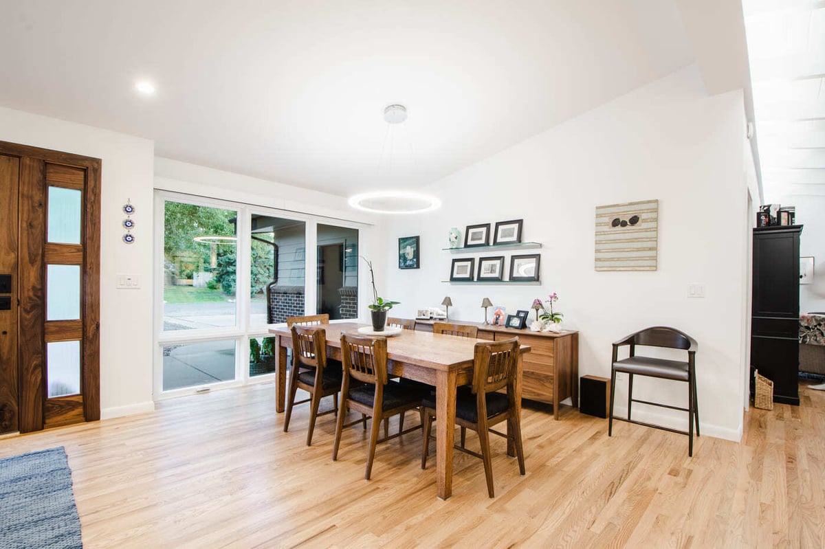 Applewood, CO renovation dining area with wood table, modern lighting, and outdoor views by Cillessen Construction