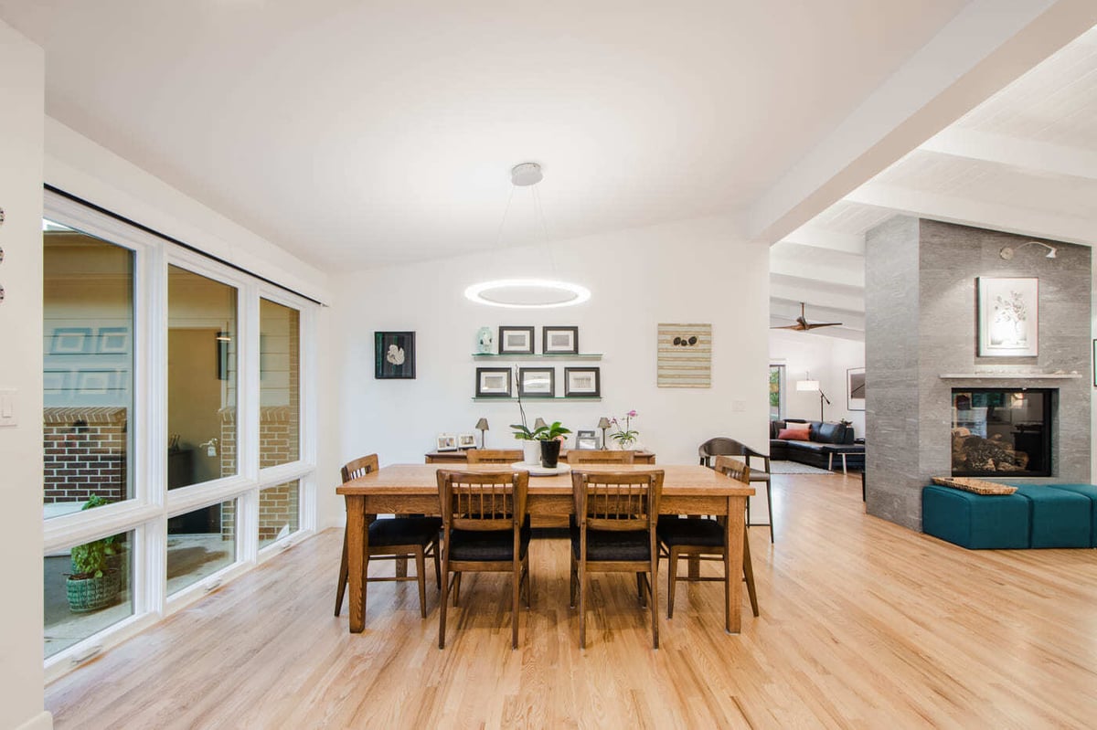 Applewood, CO renovation dining room with wood table, large windows, and open layout by Cillessen Construction