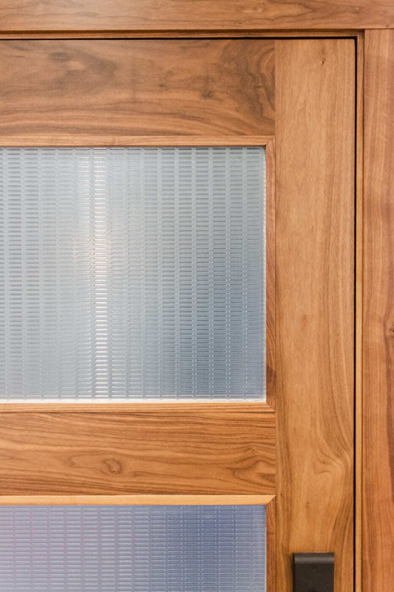 Applewood, CO renovation door detail with wood frame and frosted glass panel by Cillessen Construction