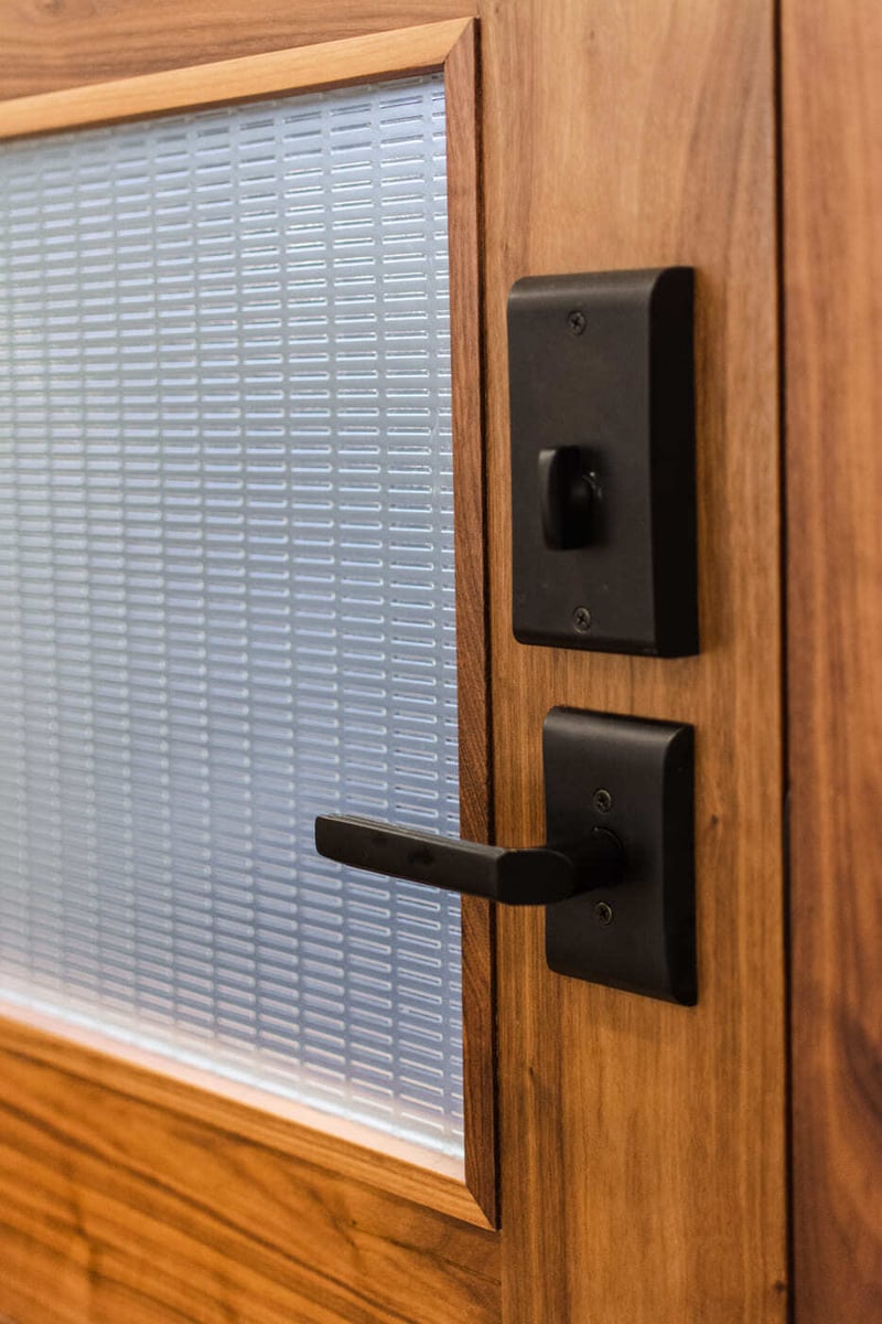 Applewood, CO renovation door hardware detail with black handle on wood and frosted glass by Cillessen Construction