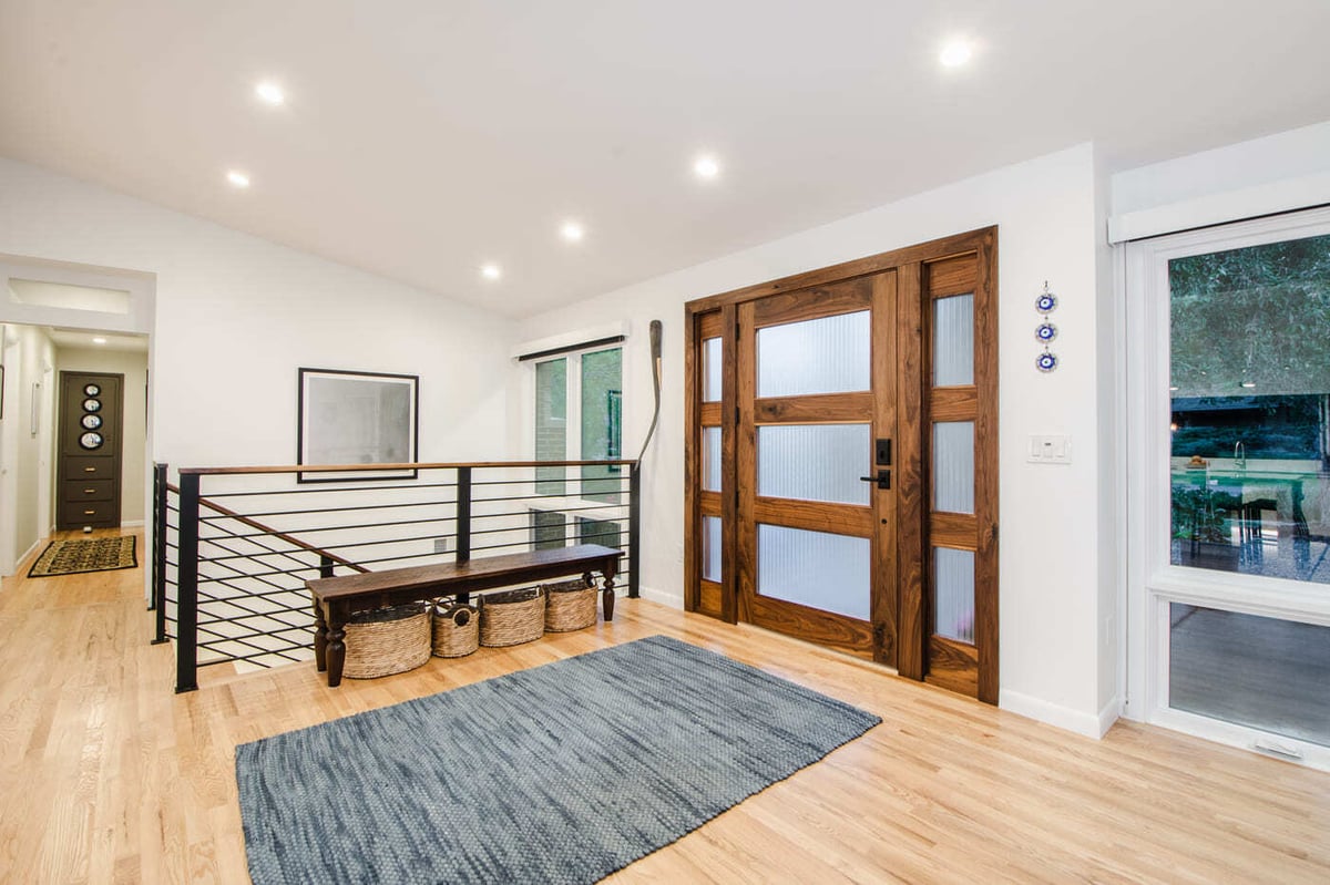 Applewood, CO renovation entry with wood front door, modern railing, and open layout by Cillessen Construction