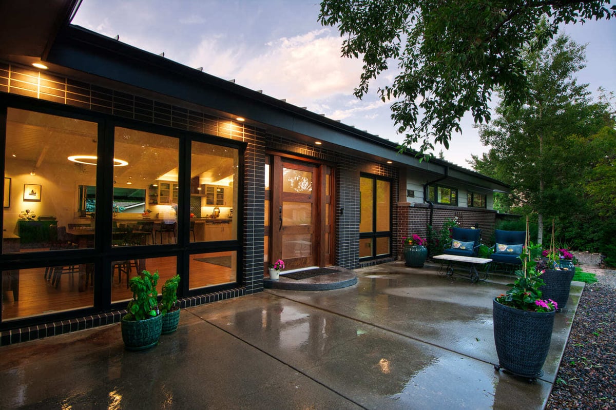 Applewood, CO renovation exterior with lit windows, patio seating, and landscaped yard by Cillessen Construction