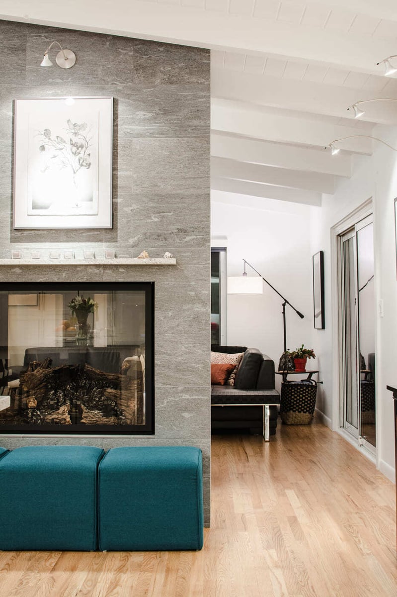 Applewood, CO renovation featuring modern fireplace wall, wood floors, and open living space by Cillessen Construction