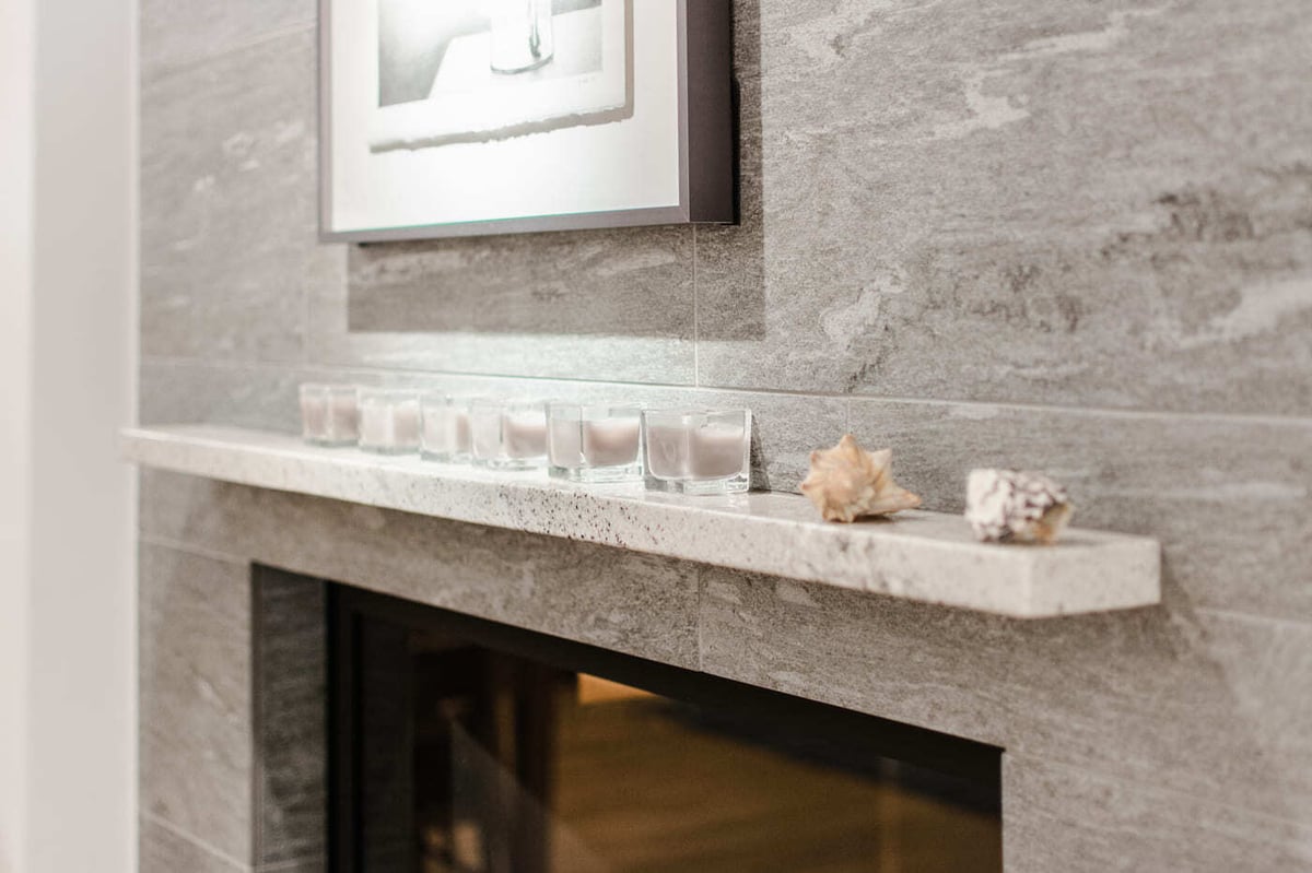 Applewood, CO renovation fireplace detail with stone surround, floating mantel, and candles by Cillessen Construction