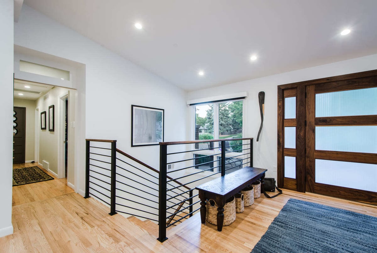 Applewood, CO renovation foyer and stair landing with wood floors and modern railing by Cillessen Construction