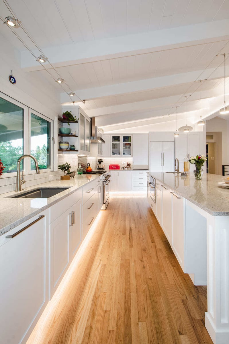 Applewood, CO renovation kitchen walkway with white cabinets, wood floors, and under-cabinet lighting by Cillessen Construction