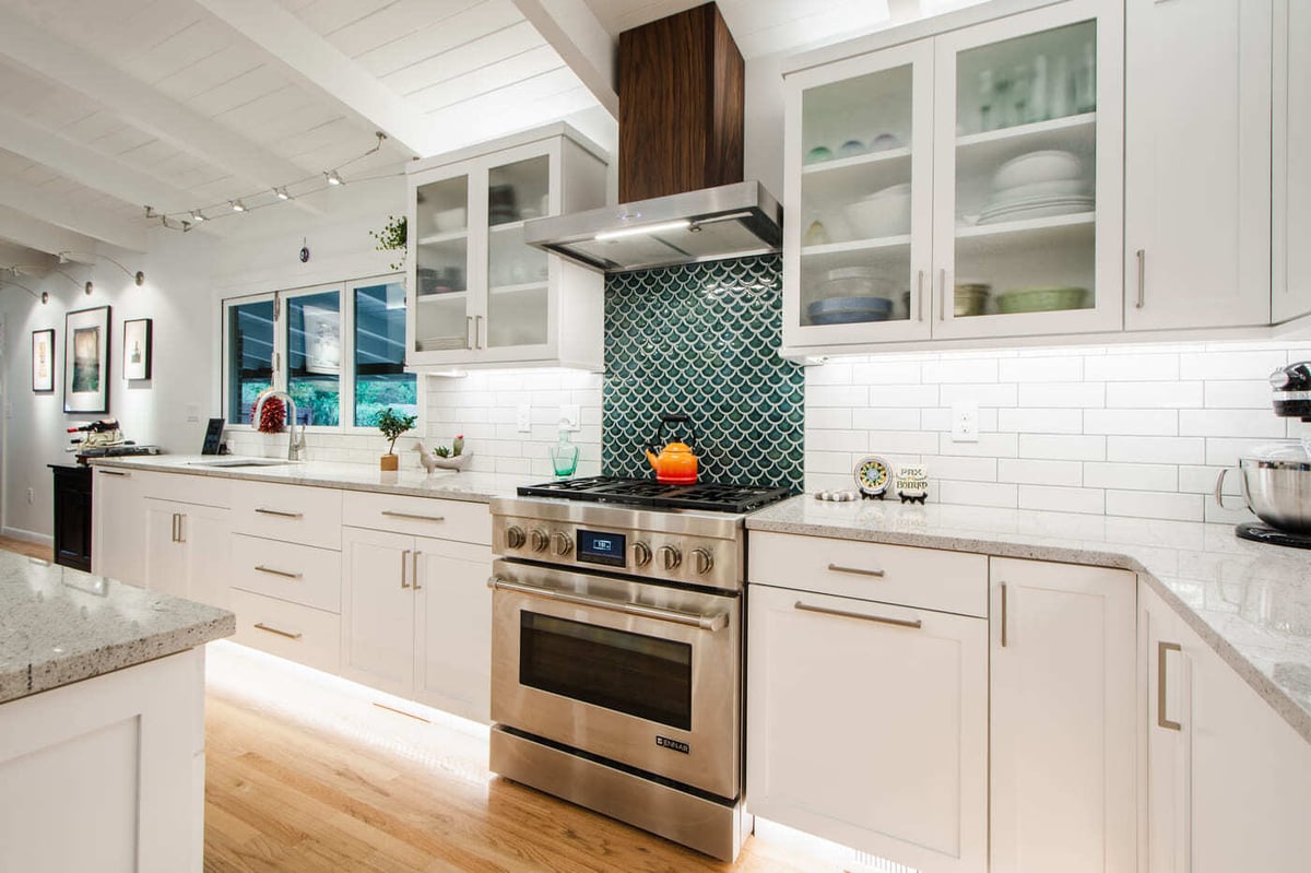 Applewood, CO renovation kitchen with gas range, white cabinets, and green tile backsplash by Cillessen Construction