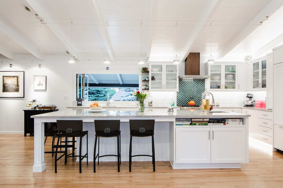 Applewood, CO renovation kitchen with large island seating, white cabinetry, and tile backsplash by Cillessen Construction