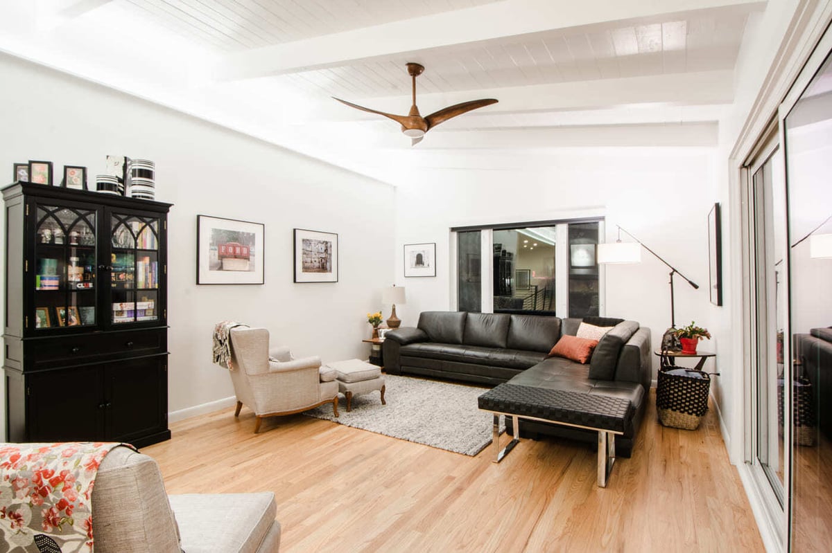 Applewood, CO renovation living room with vaulted ceiling, black sectional, and sliding doors by Cillessen Construction