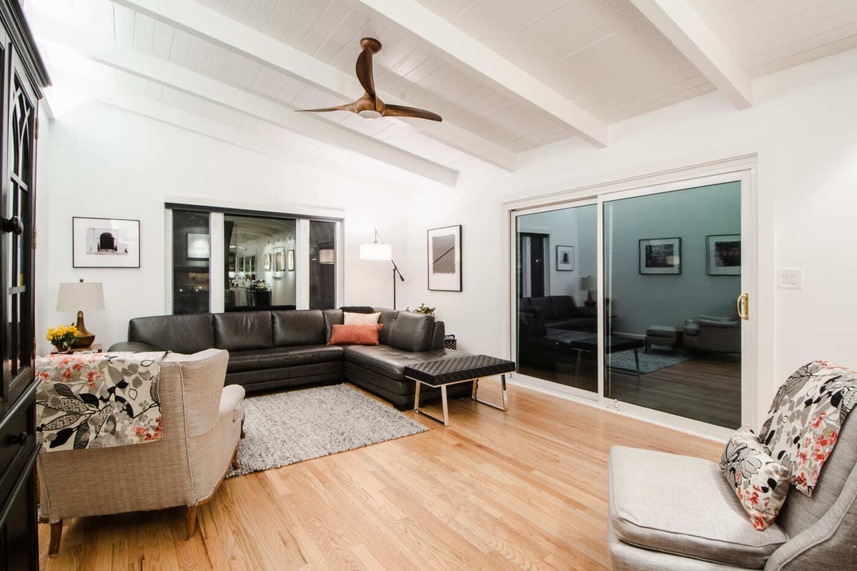 Applewood, CO renovation living room with vaulted ceilings, wood floors, and black sectional by Cillessen Construction