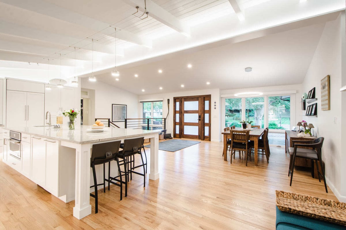 Applewood, CO renovation open kitchen and dining with large island, wood floors, and modern lighting by Cillessen Construction