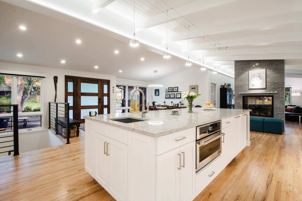 Applewood, CO renovation open kitchen with large island, modern fireplace, and wood floors by Cillessen Construction